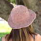 Person wearing a pink woven hat in a park setting