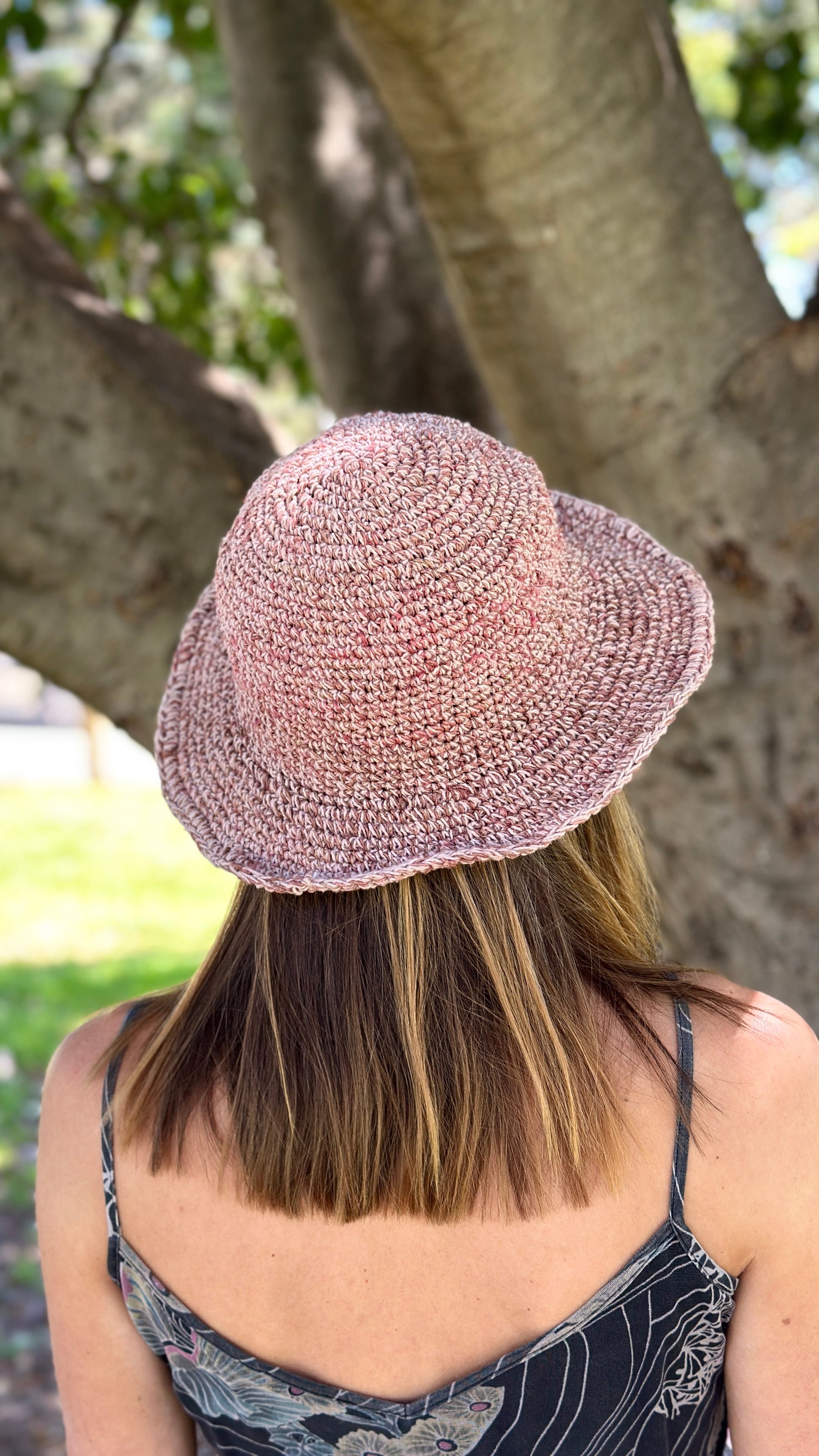 Person wearing a pink woven hat in a park setting