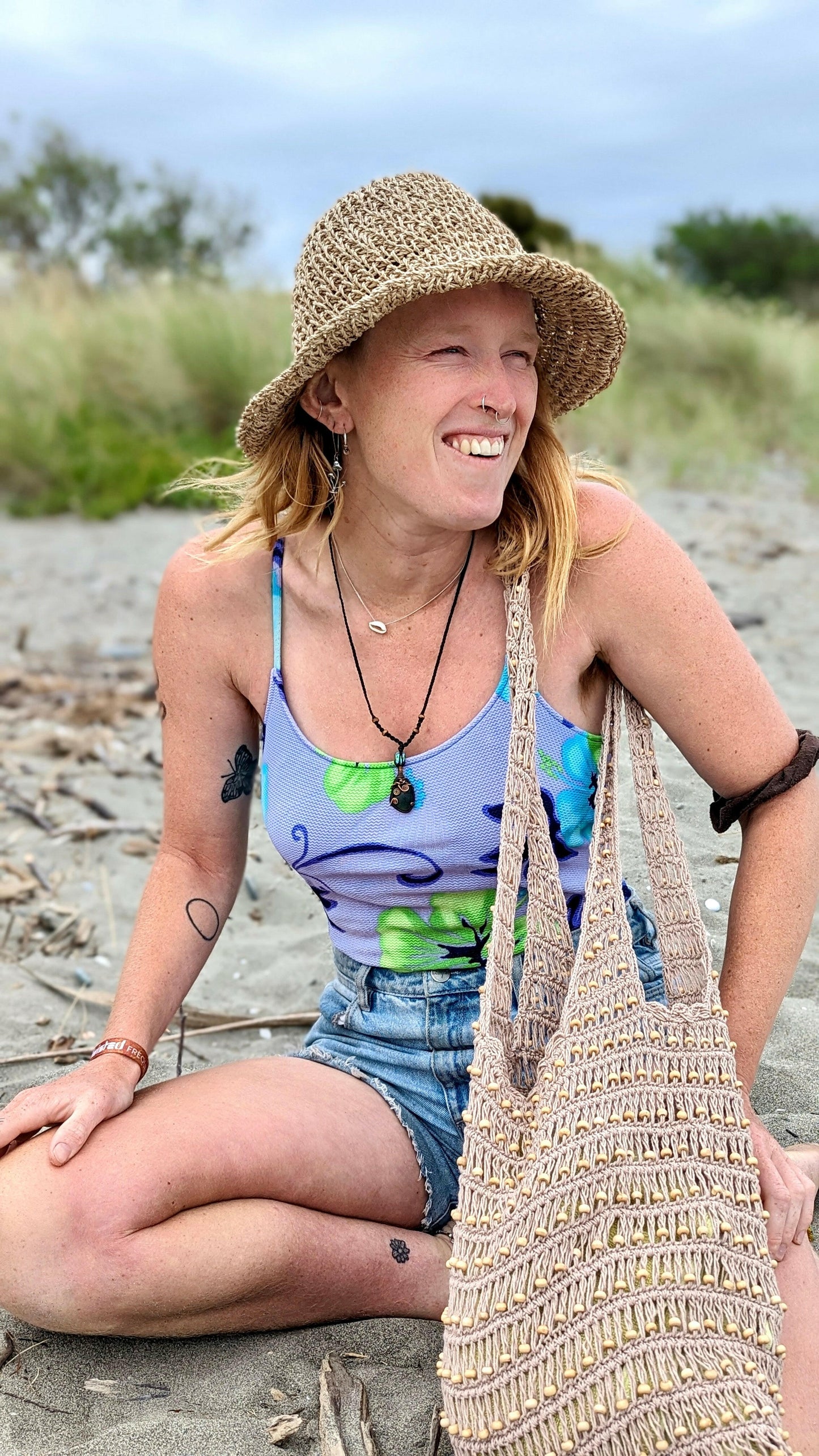 Girl smiling while wearing sustainable bucket hat and tote bag on beach