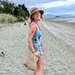 Girl smiling while wearing hemp hat and sustainable tote bag on beach in New Zealand